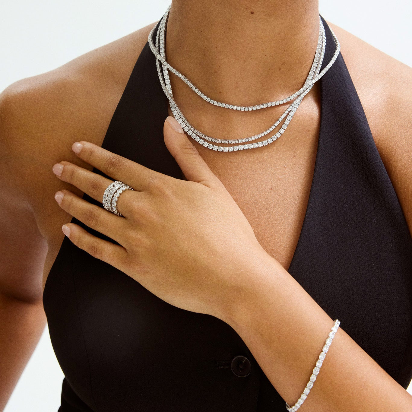 Woman wearing a 14k diamond tennis necklace, ring, and bracelet on a white background