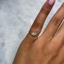 Gold ring with a diamond on a person's finger against a marble background