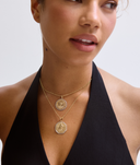 Woman wearing a black halter top with gold necklaces on a white background