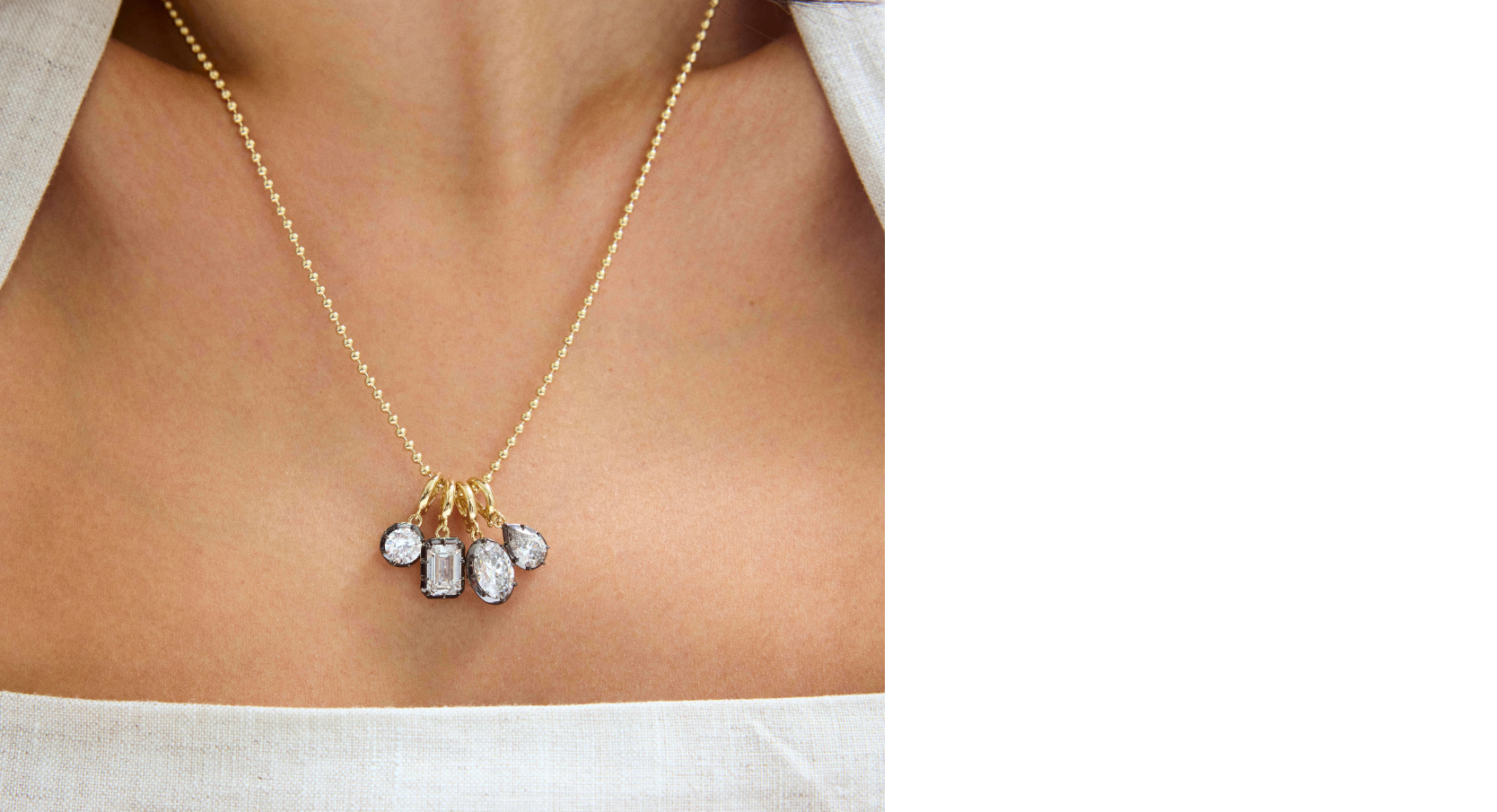Gold necklace with small pendants on a person wearing a white top.